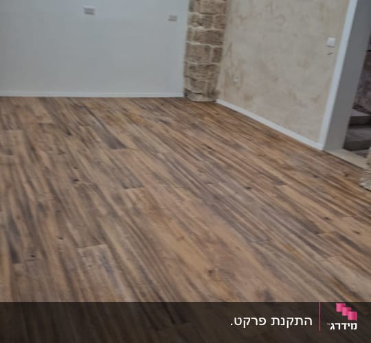 רצפת פרקט בחדר עם קירות אבן ותאורה